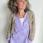 Lächelnde Frau in lila Bluse und Strickjacke