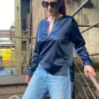 Frau in Jeans und Bluse vor Industriegebäude