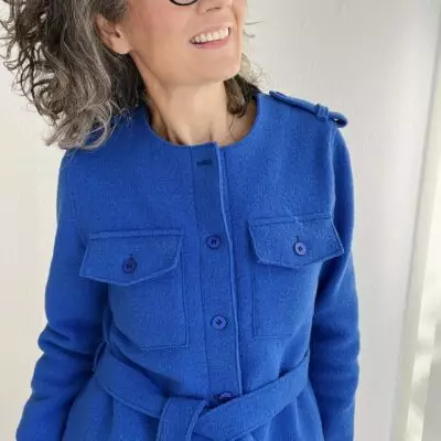 Frau in blauer Jacke lächelt zufrieden.