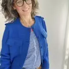 Frau in blauer Jacke und Brille lächelt