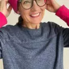 Frau lächelt mit pinker Mütze und Brille