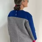 Frau im grauen und blauen Pullover von hinten